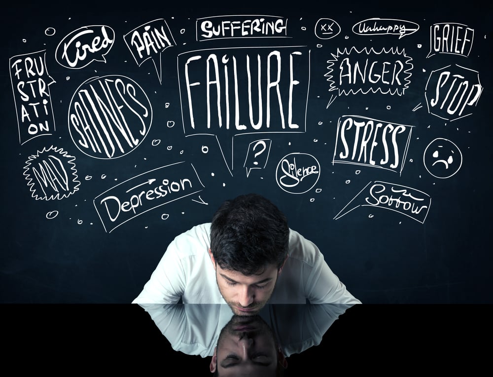 Young depressed businessman sitting under white drawn trouble thought boxes